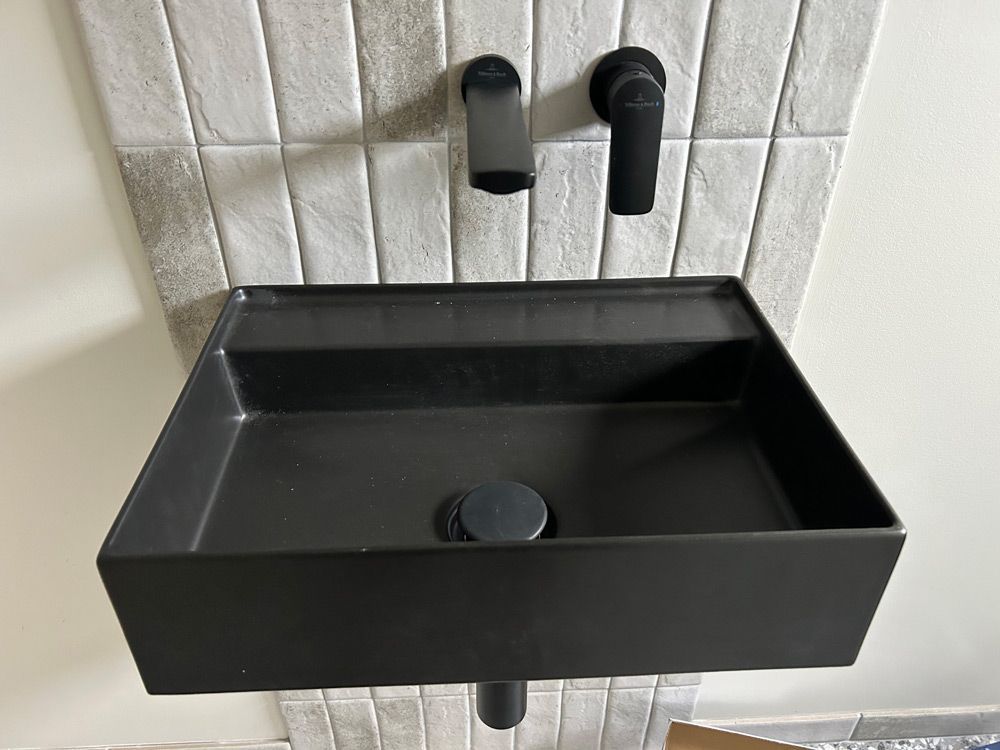 A Black Sink Is Mounted To A Wall In A Bathroom — Taps & Toilets in Mittagong, NSW