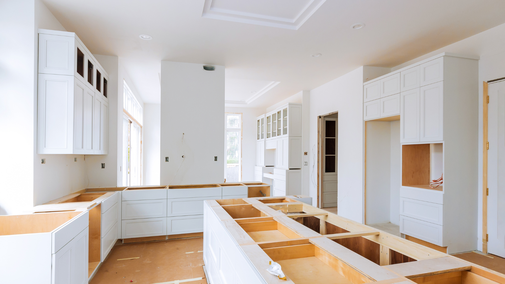 A kitchen under construction with white cabinets and wooden counter tops.