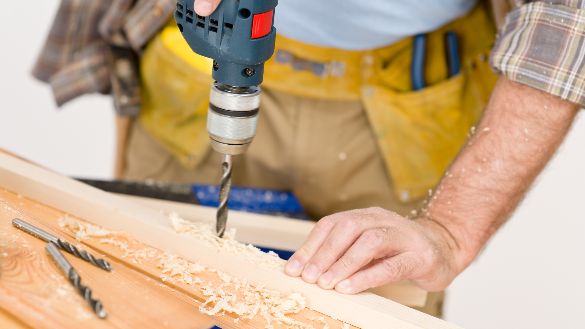 A man is using a drill to drill a hole in a piece of wood.