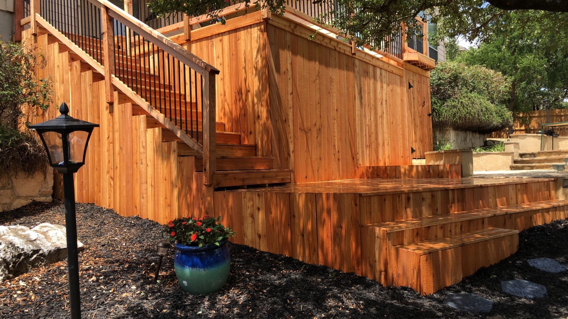 A wooden deck with stairs and a lamp post in front of it.