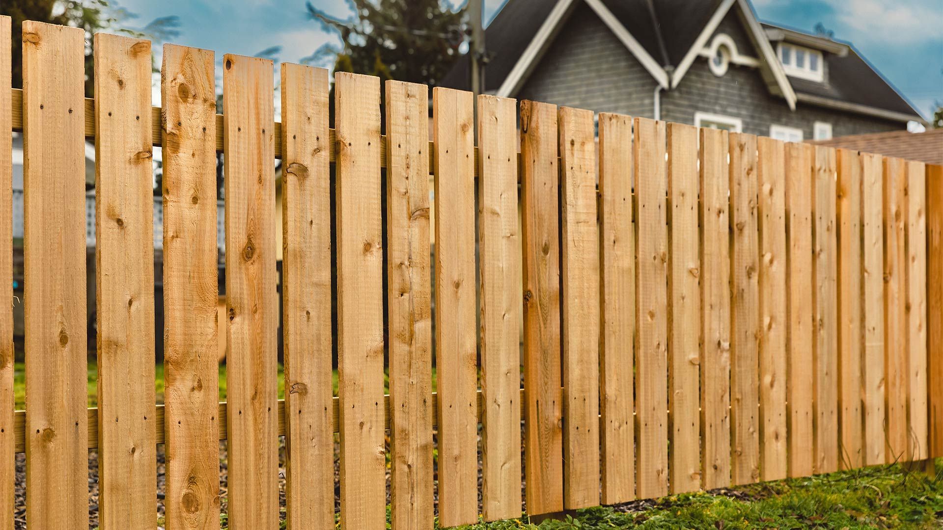 A wooden fence is in front of a house.