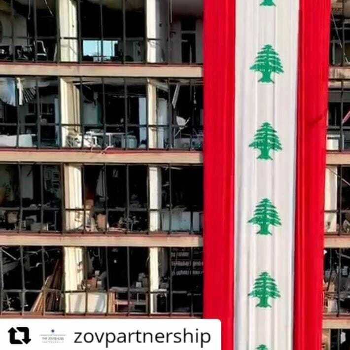 A screenshot of the youtube banner featuring a huge Lebanese flag hung on a damaged building.