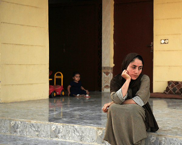 Yazidi woman sits outside her house