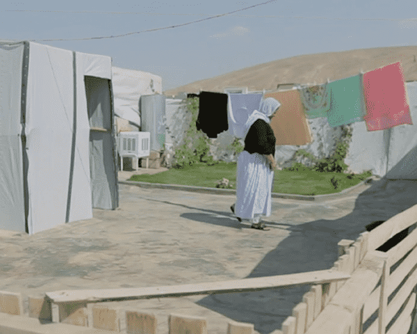 Yazidi woman hangs clothes to dry outside the tent