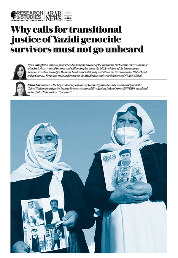 Two Yazidi veiled women hold portraits of Yazidi victims