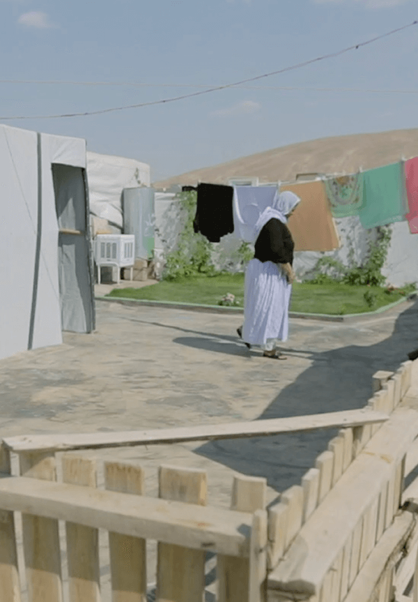 Yazidi woman hang clothes to dry outside