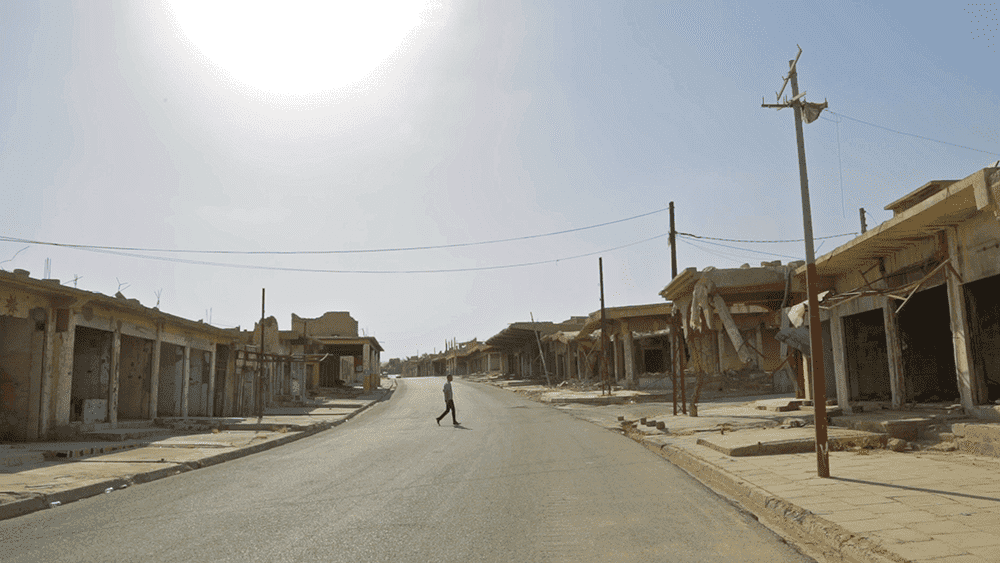A man walks between the destroyed buildings in Sinjar