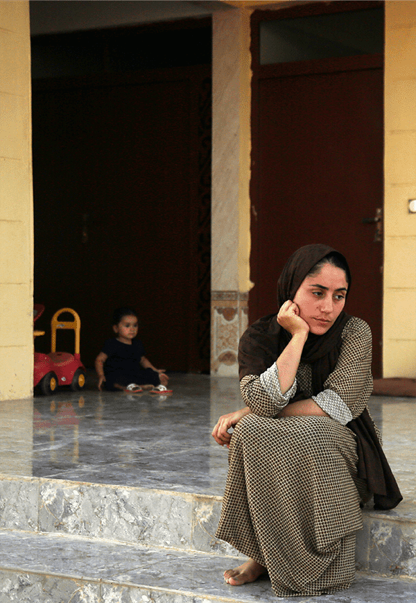 Yazidi woman sits outside her house