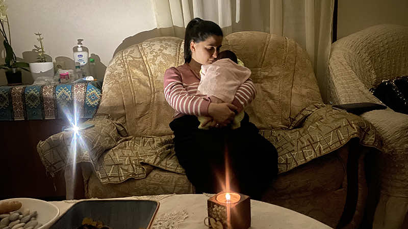 Another holding her newborn, sitting on a couch in Artsakh