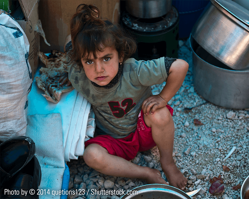 A Yazidi young girl siting on the floor in a refugee tent