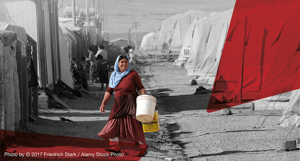 A Yazidi woman carrying a bucket at a Yazidi refugee camp
