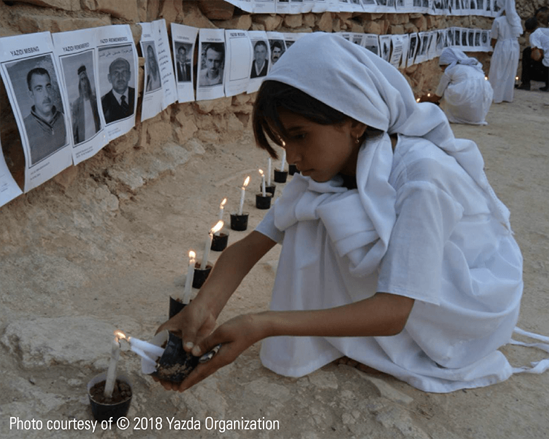 Yazidi girl lighting candles to commemorate the victims of the Yazidi Genocide