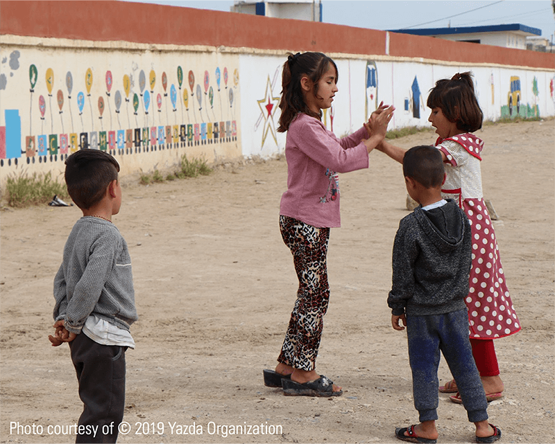 Displaced Yazidi children play outside in a camp