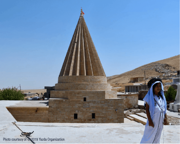 Yazidi girl wearing traditional clothing in-front of a Yazidi Temple
