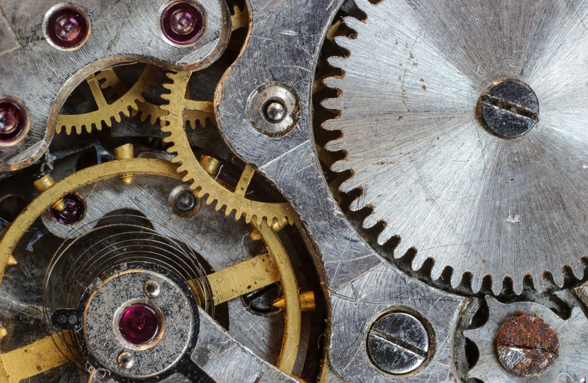 A close up of a clock mechanism with a red stone in the middle