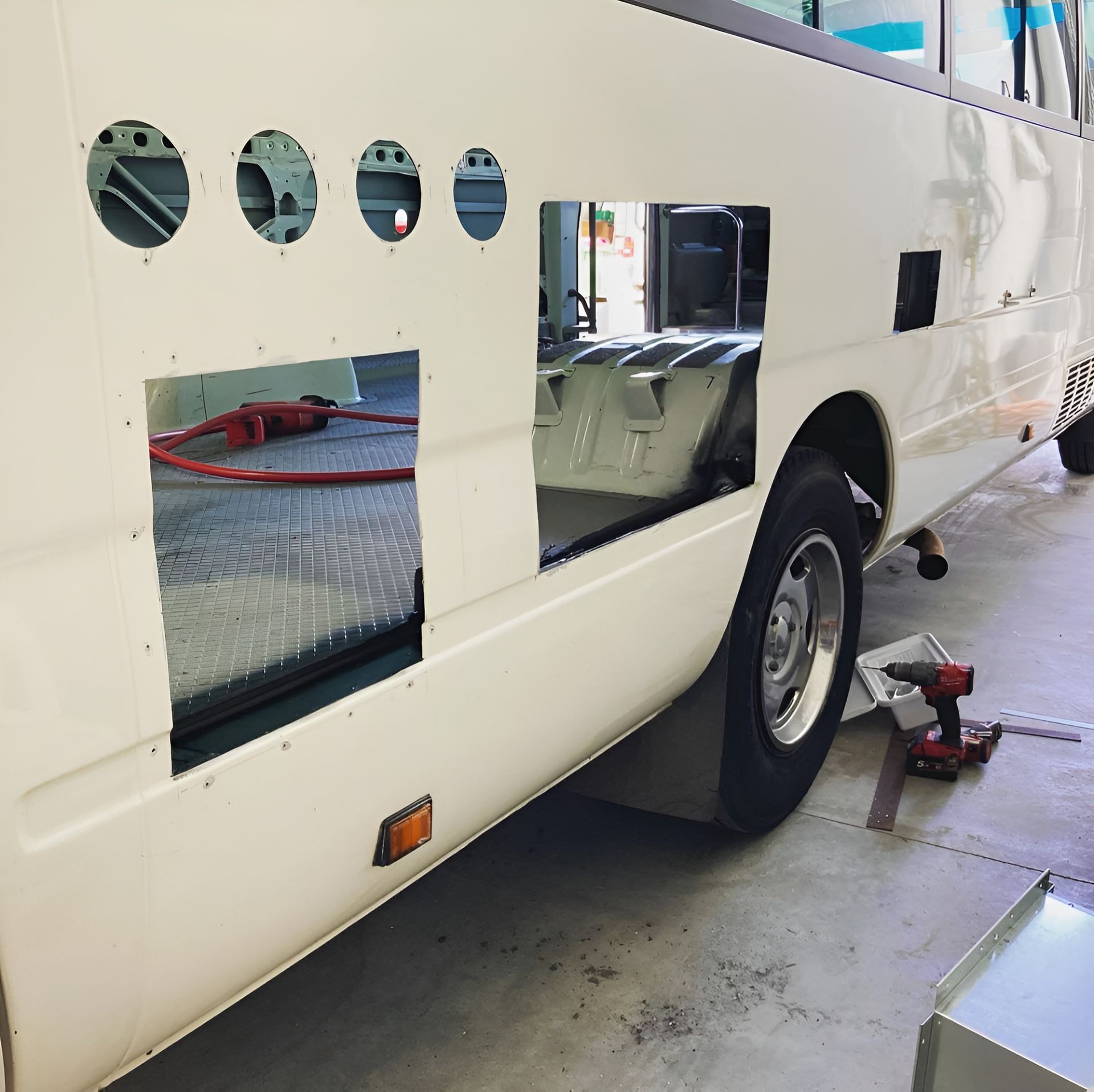 A White Bus With Holes In The Side Is Being Worked On — Live Unbound Campers In Gold Coast, QLD