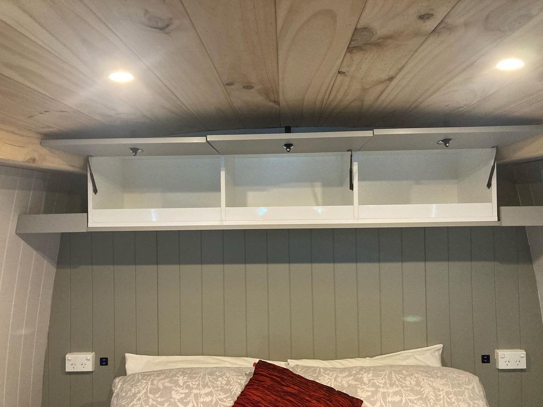 A Bedroom With A Bed And A Shelf Above It — Live Unbound Campers In Upper Coomera, QLD