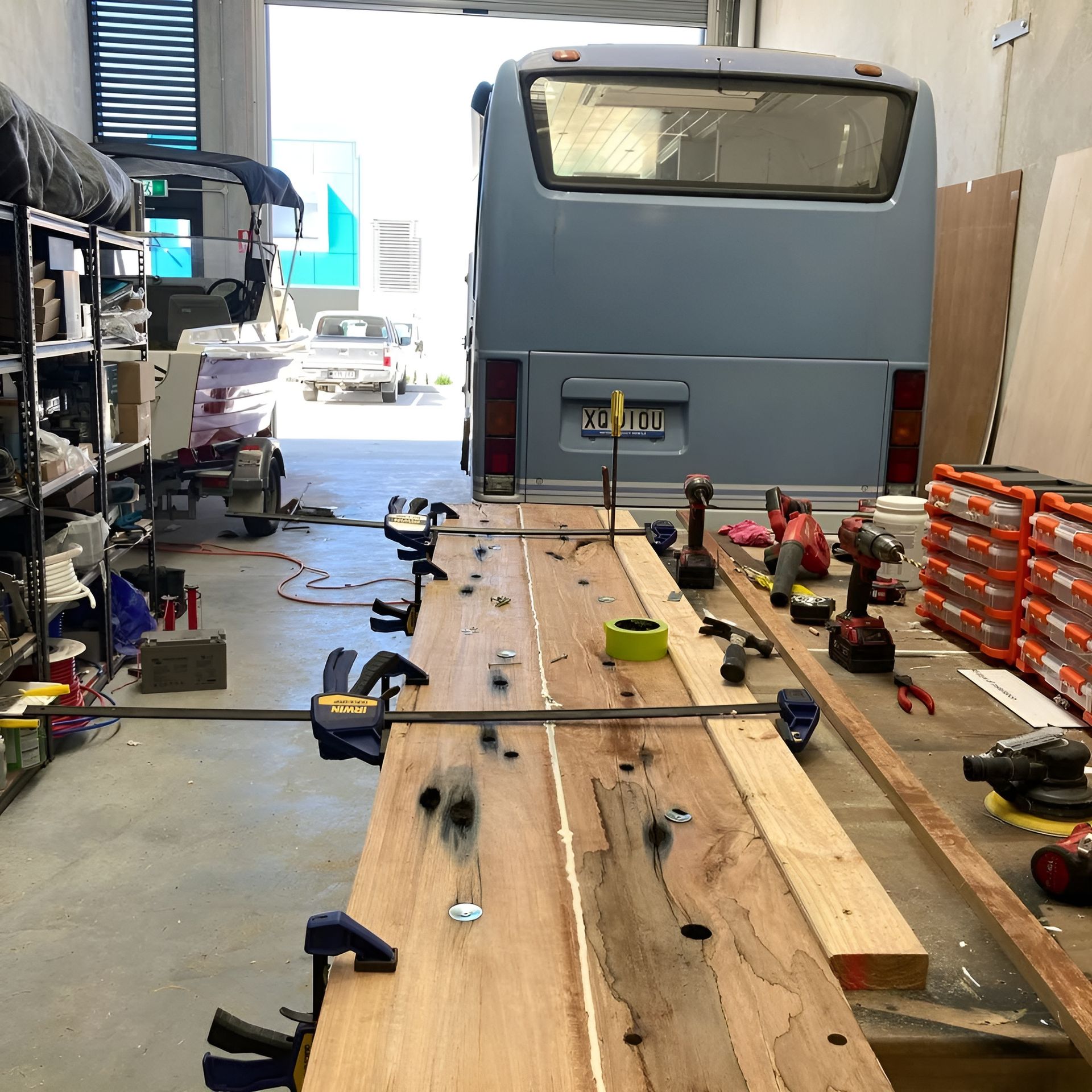 A Bus Is Parked In A Garage Next To A Wooden Table — Live Unbound Campers In Brisbane, QLD