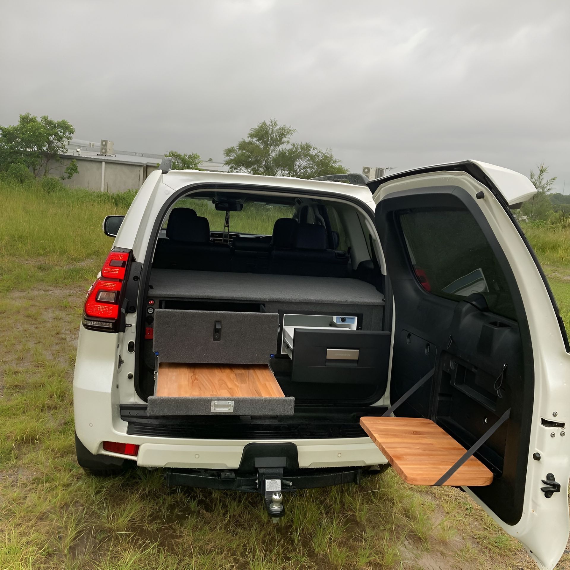 A White SUV Is Parked In A Grassy Field With The Door Open — Live Unbound Campers In Upper Coomera, QLD