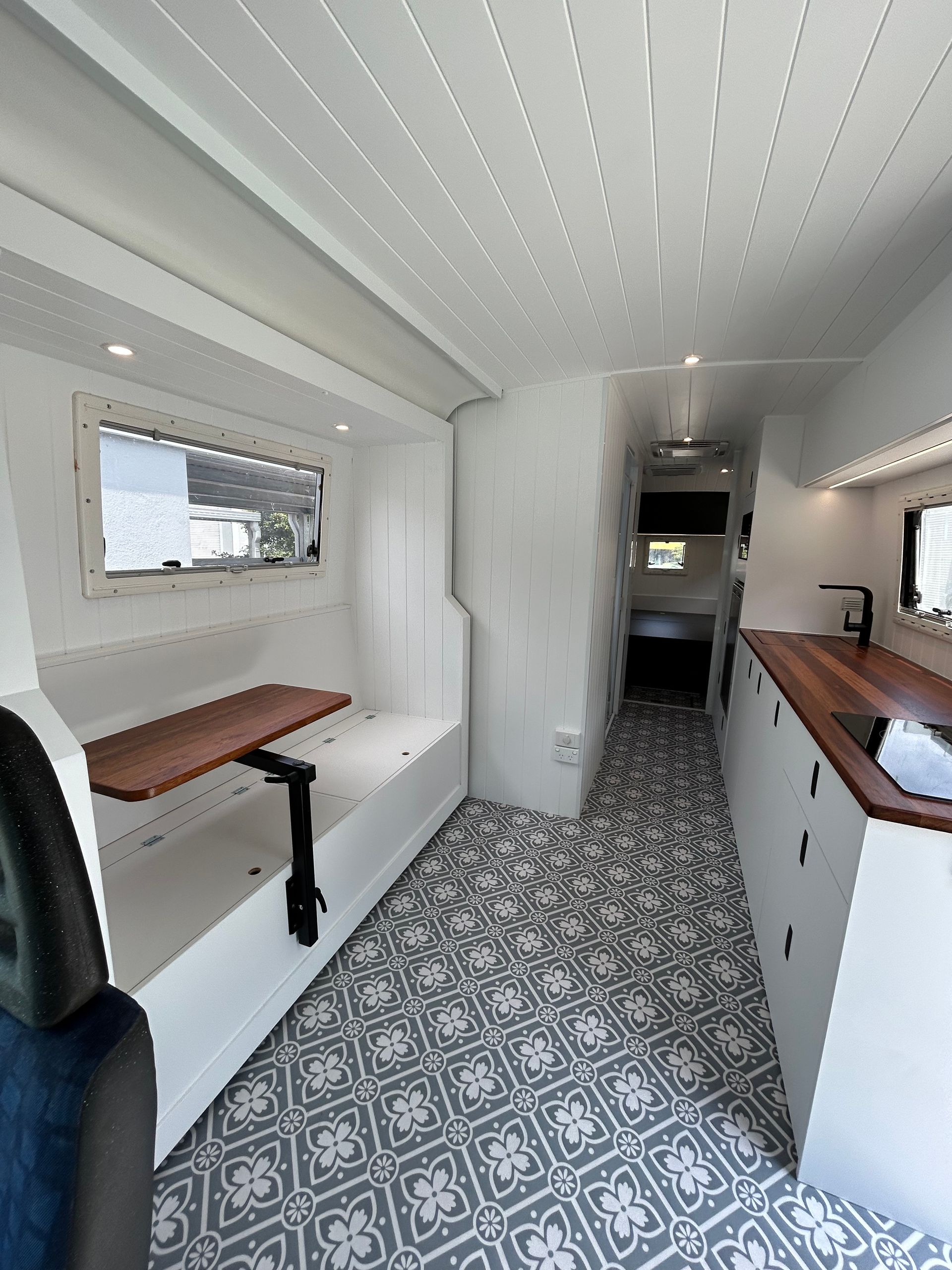 A Kitchen With A Wooden Counter Top, Stove, And Television — Live Unbound Campers In Upper Coomera, QLD