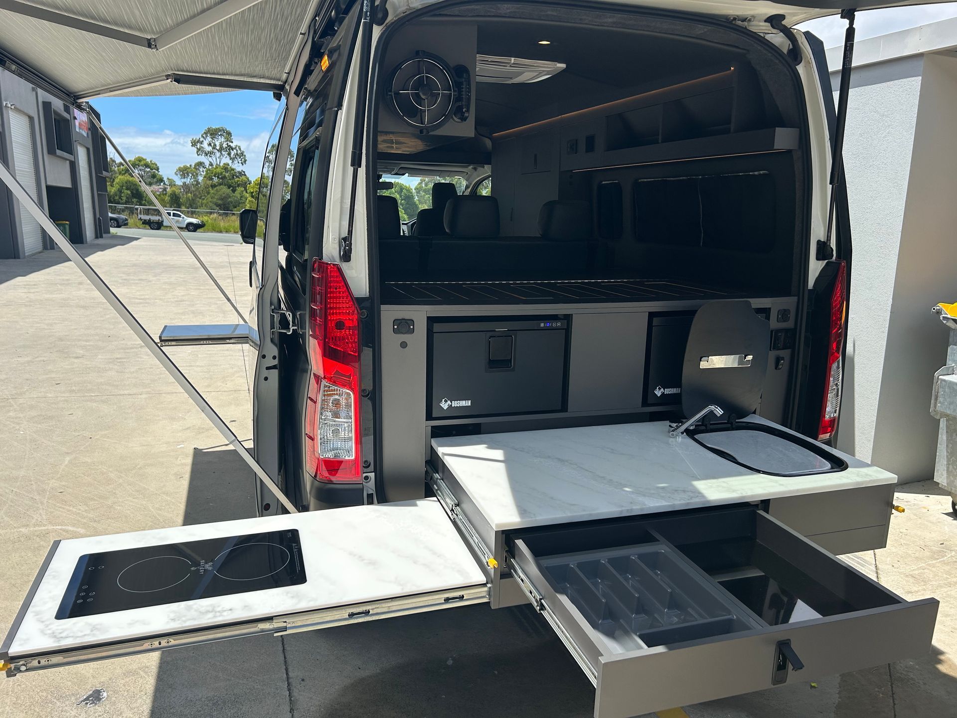 A Large White Bus Is Parked In A Garage — Live Unbound Campers In Upper Coomera, QLD