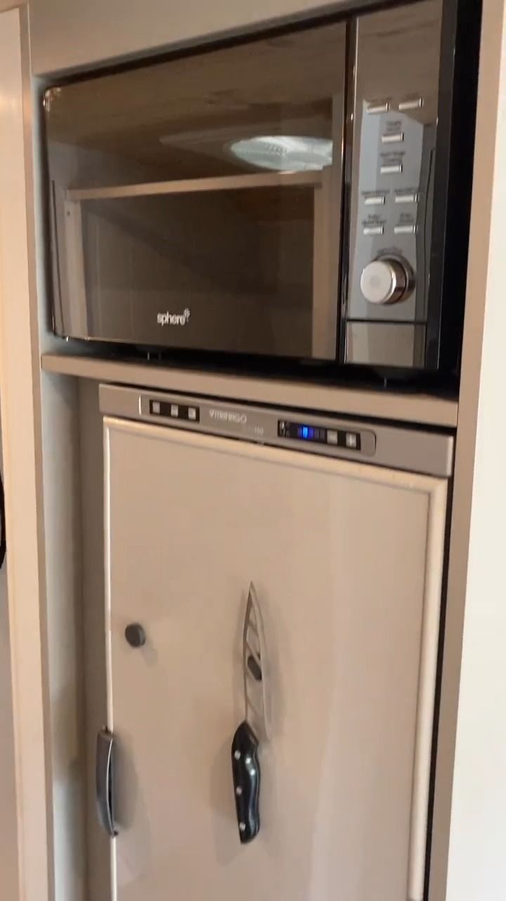 A Microwave Is Above A Refrigerator In A Kitchen — Live Unbound Campers In Upper Coomera, QLD