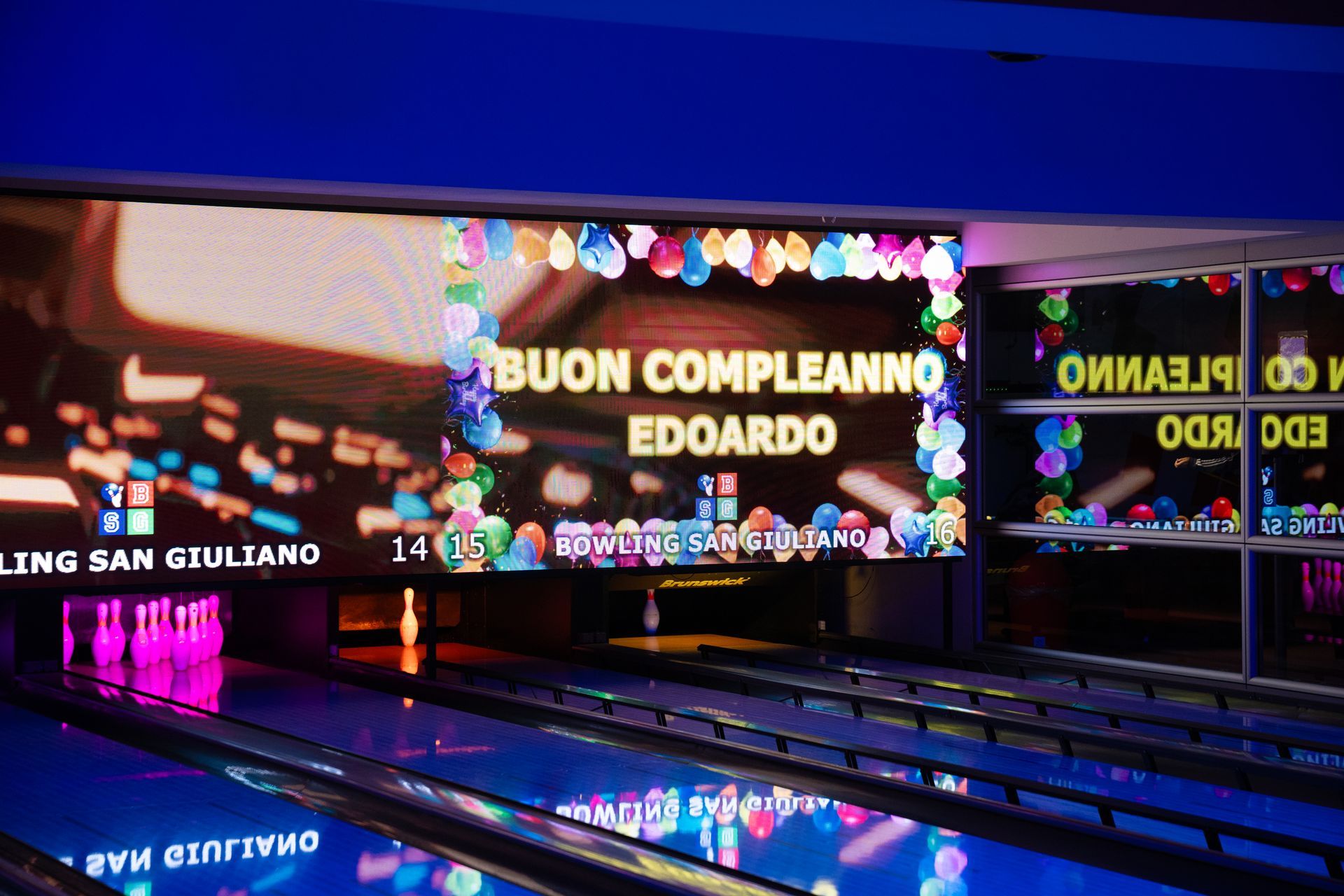 Sala giochi con diverse macchine da gioco ben illuminate. Una scala con dettagli rossi conduce al piano superiore.