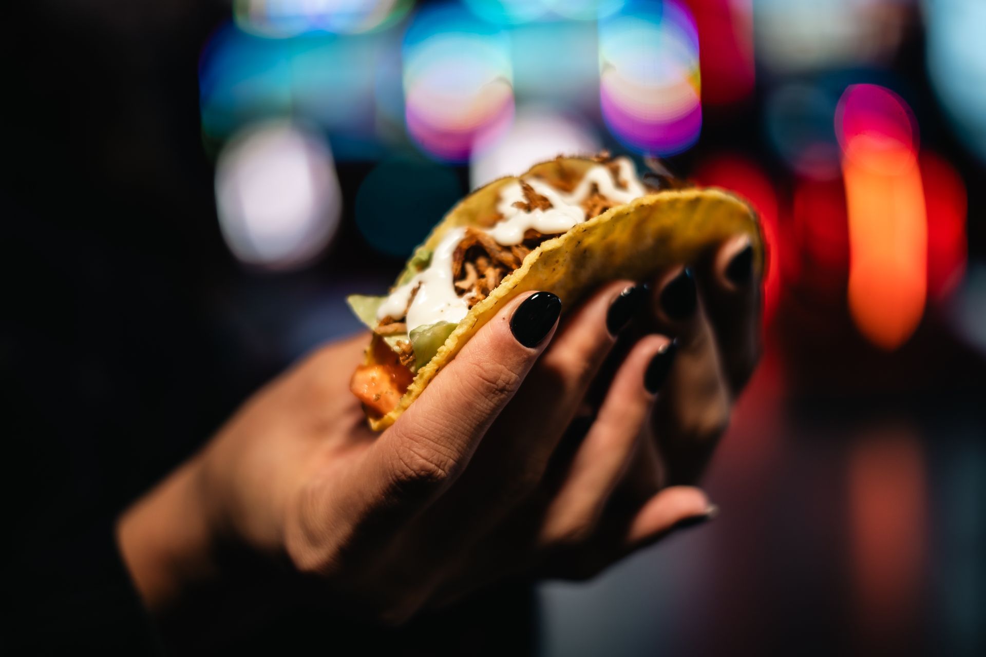 Persona che gioca a bowling e lancia una palla blu lungo una pista da bowling illuminata al neon.