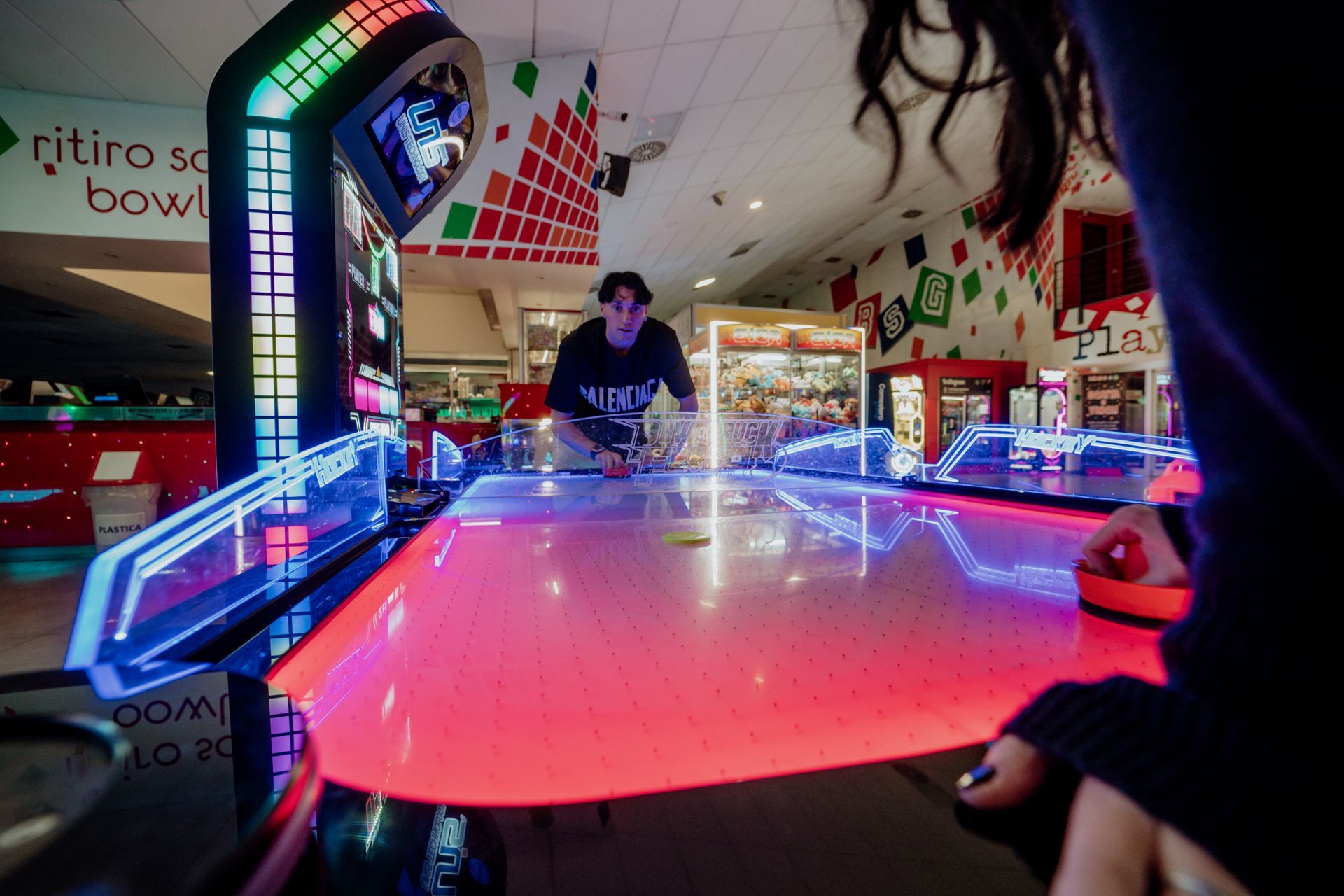 Sala giochi arcade con diverse macchine da gioco, dettagli rossi e illuminazione dall'alto.