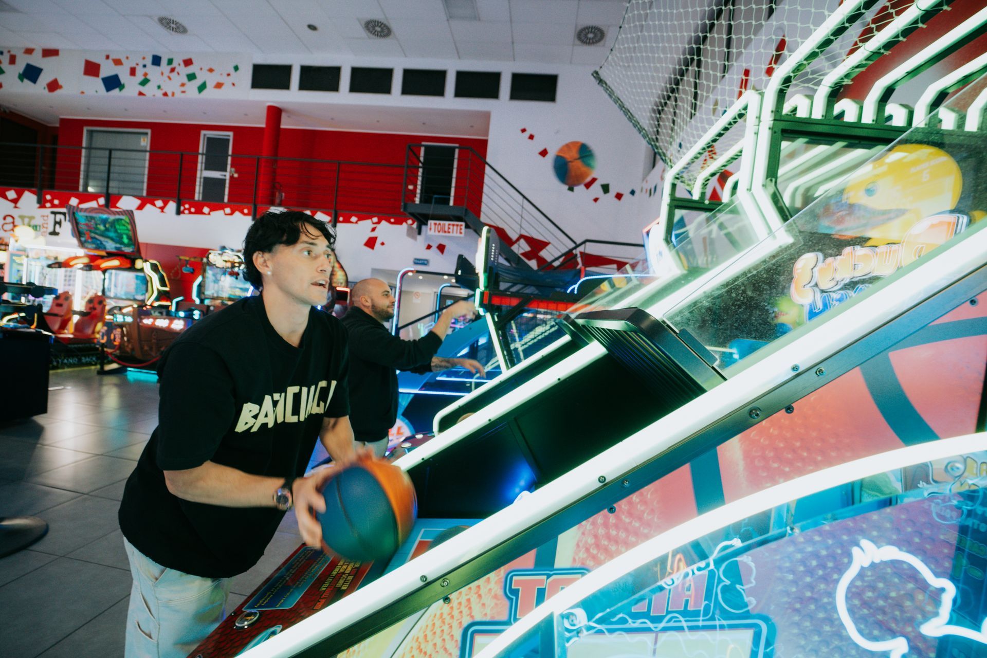 Interno della pista da bowling con illuminazione blu, piste, schermi e posti a sedere.