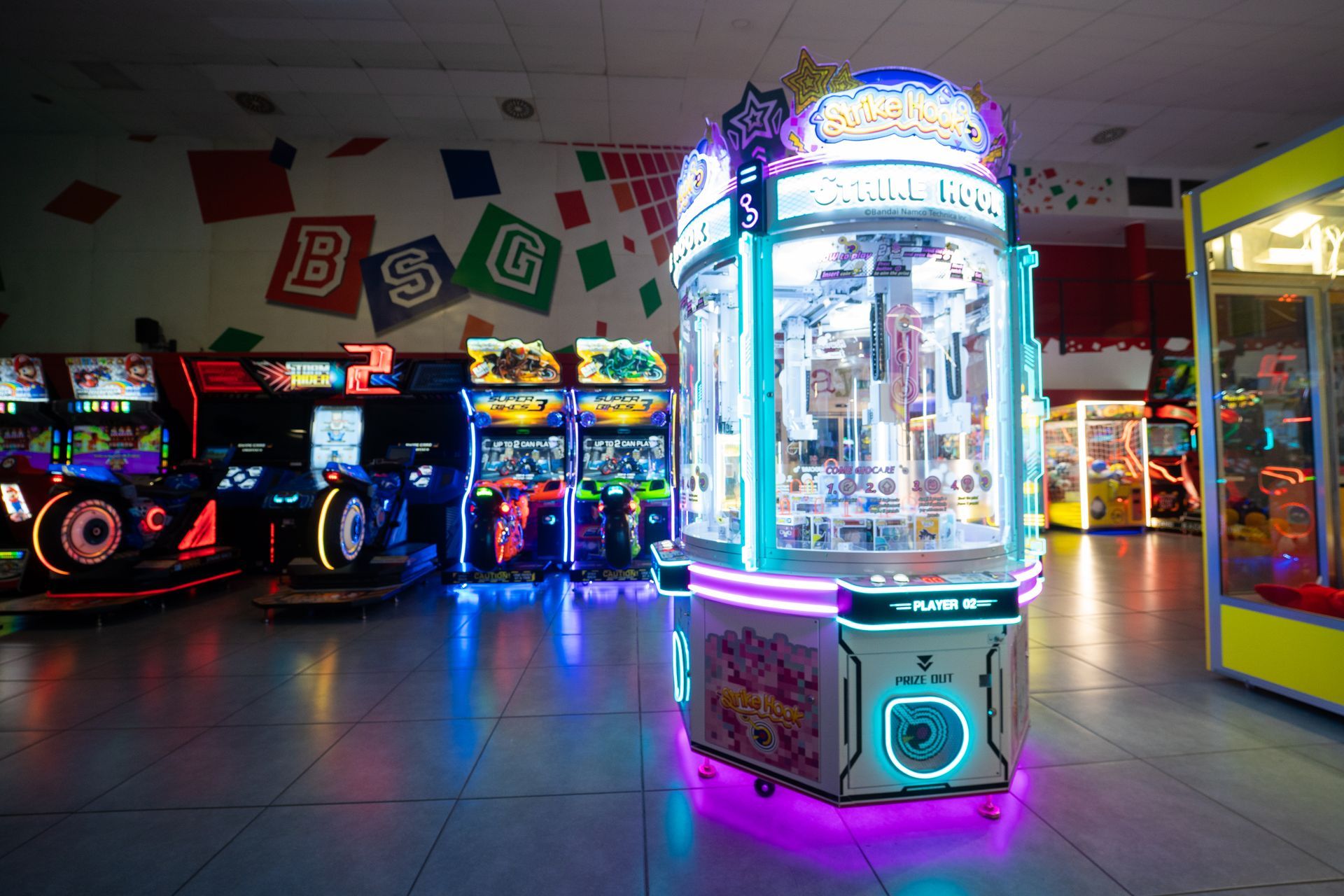 Palle da bowling di vari colori su rastrelliere di ritorno, piste sullo sfondo, persona in silhouette.