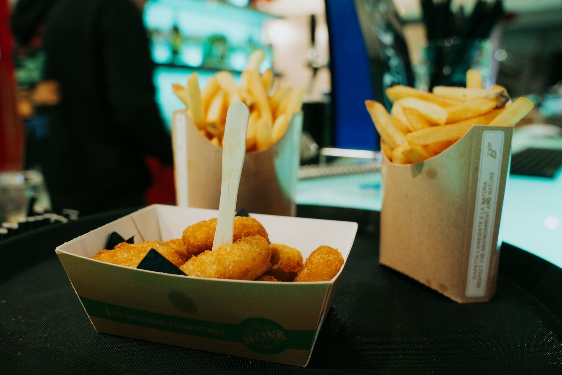 Hamburger su un piatto di legno, avvolto nella carta, con lattuga e pomodoro, in un ristorante.