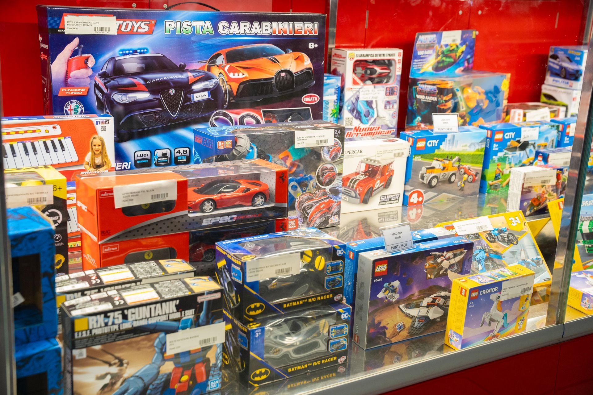 Interno della sala da biliardo con file di tavoli da biliardo in feltro verde, tappeto rosso e decorazioni murali colorate.