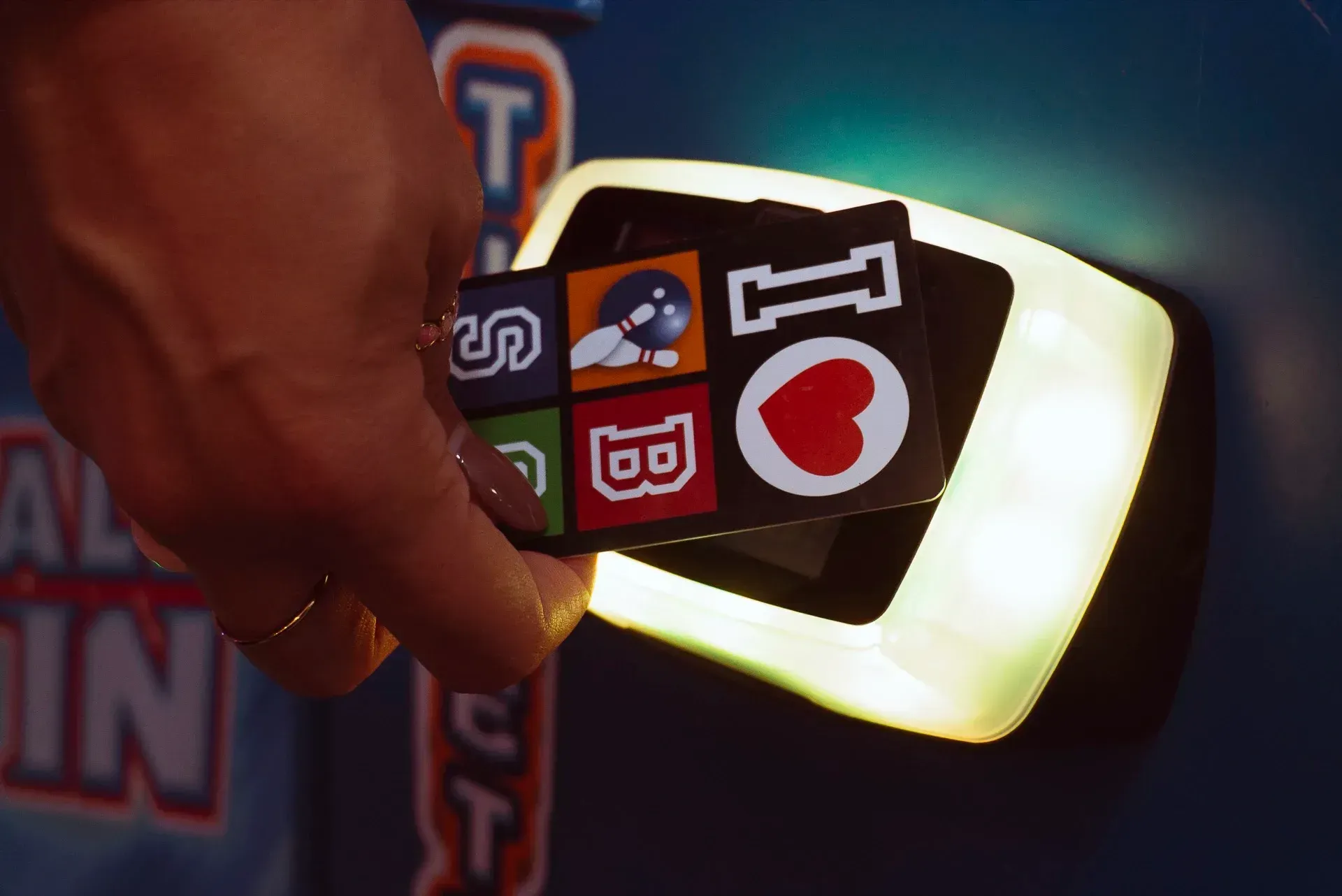 Mano che inserisce una scheda di gioco con icone in un lettore luminoso.