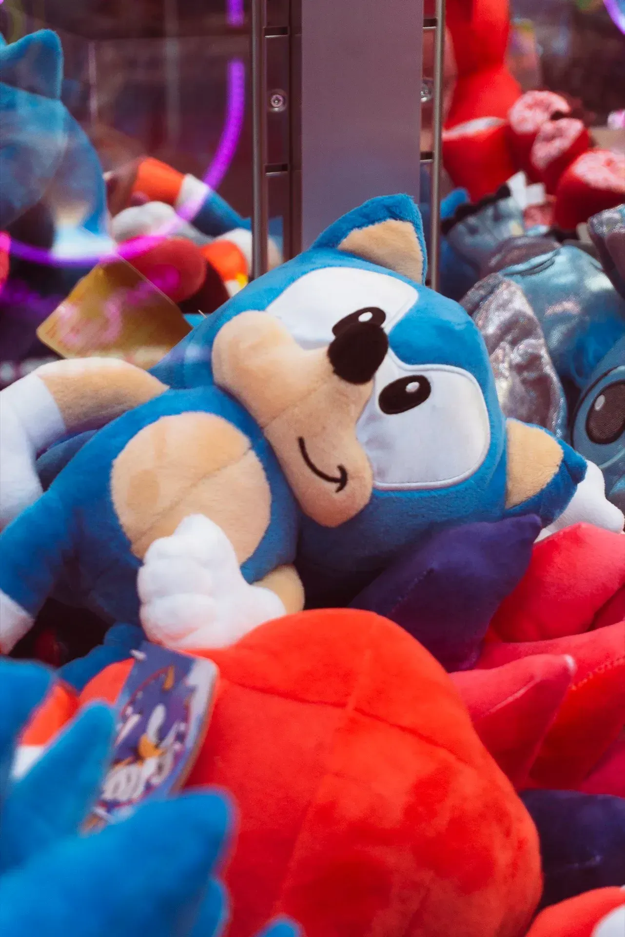 Peluche di Sonic the Hedgehog in una macchina artiglio con altri giocattoli colorati.
