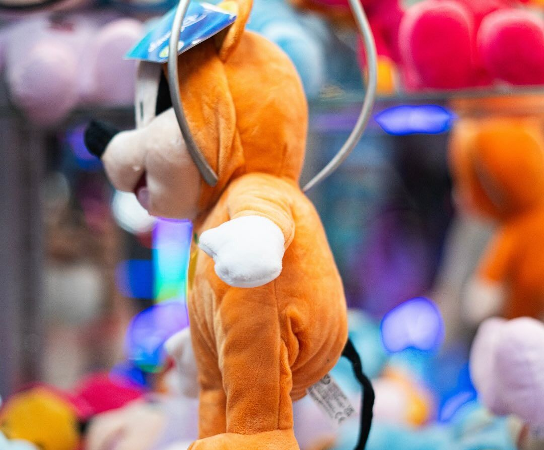 Cane di peluche arancione sollevato da una macchina artigliante.