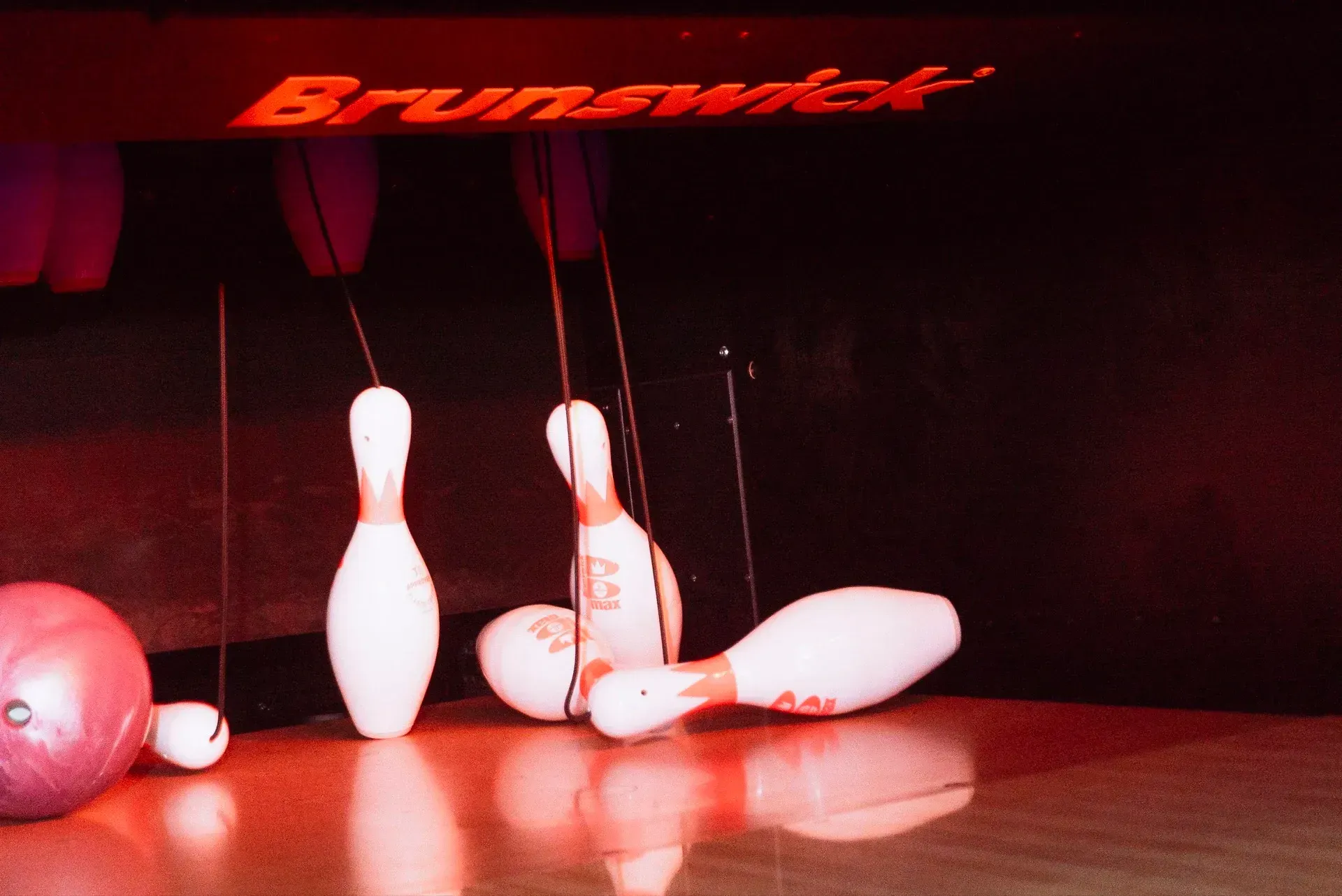Birilli abbattuti su una pista con una palla da bowling. Il logo della Brunswick in rosso sopra.