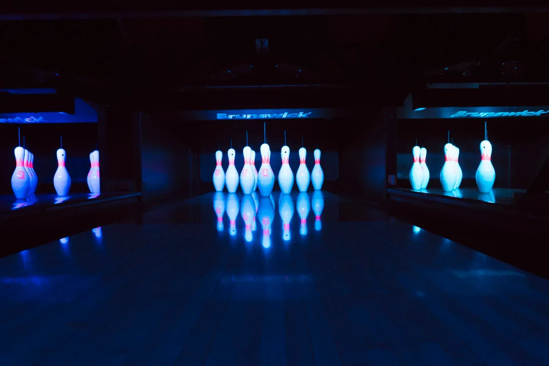 Birilli illuminati con luce blu in una pista da bowling buia.