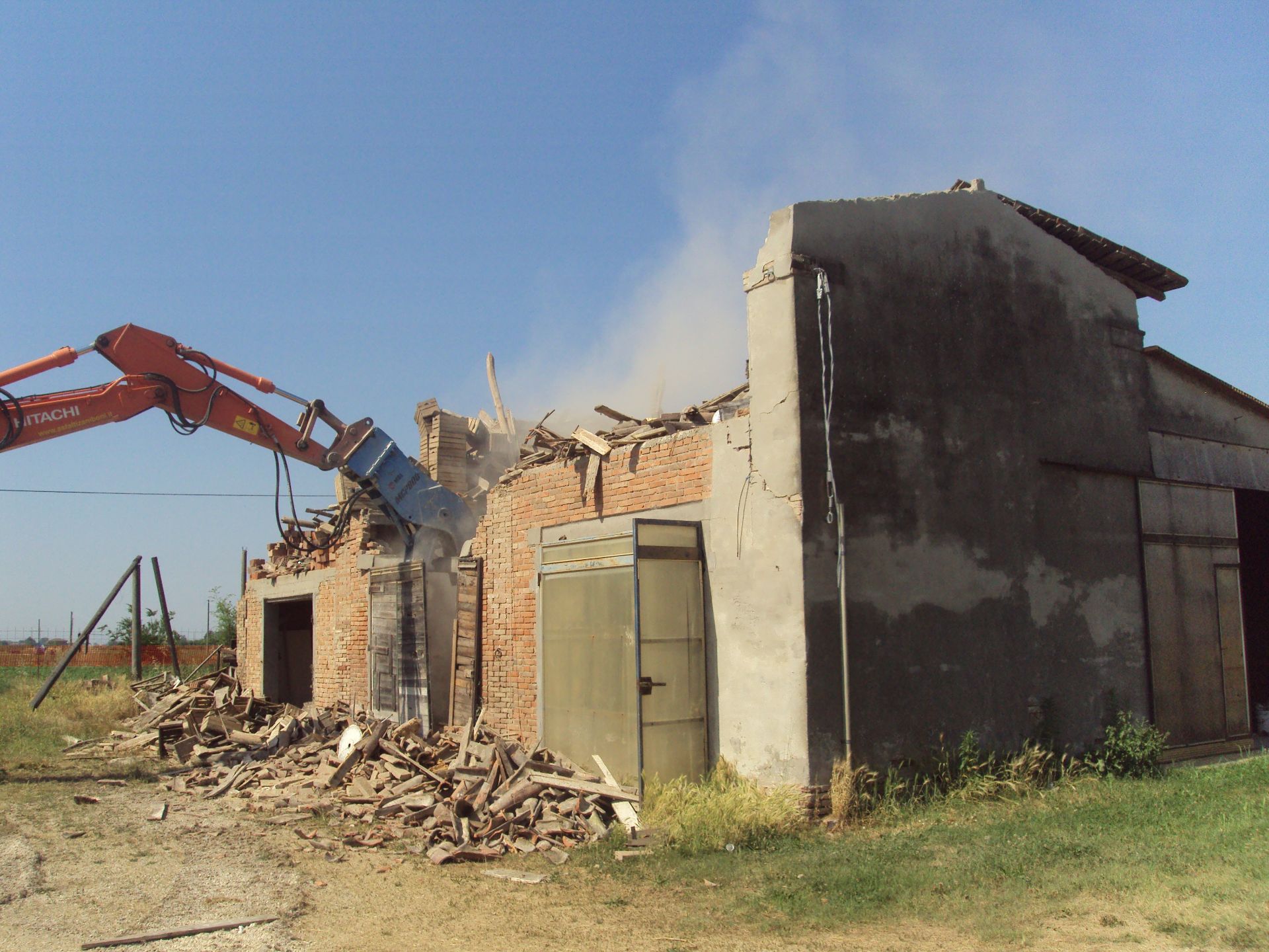Mezzo con pinza frantumatrice abbatte un rudere