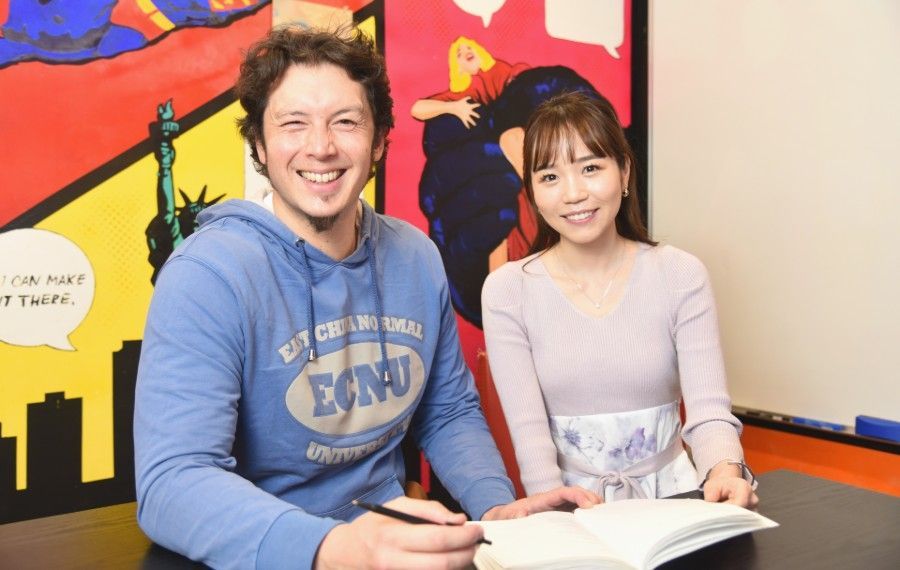 A man and a woman are sitting at a table with a book.