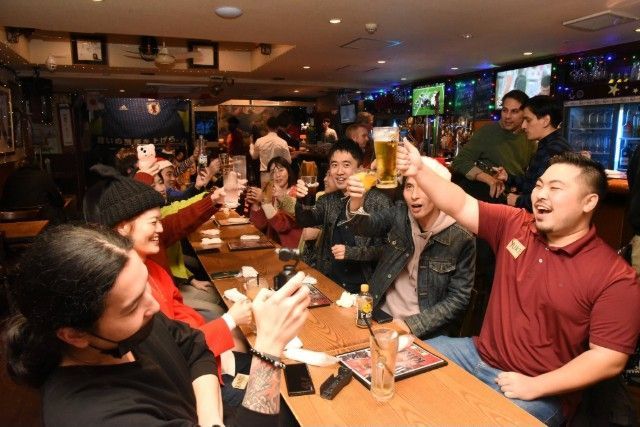 People toasting with beer glasses in a crowded bar. Cheers!