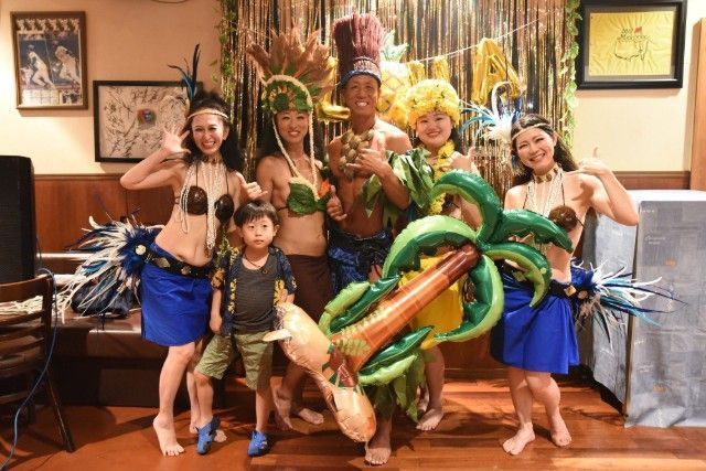 Group of people in Hawaiian outfits posing with inflatable palm tree.