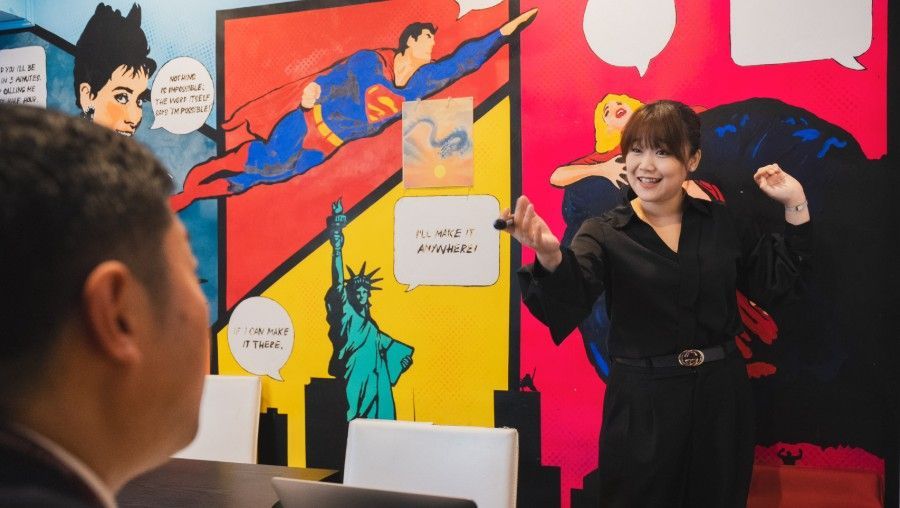 Woman posing in front of colorful comic-style mural while a man watches from the foreground