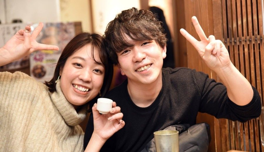 居酒屋で飲みながら笑顔でポーズをする男女