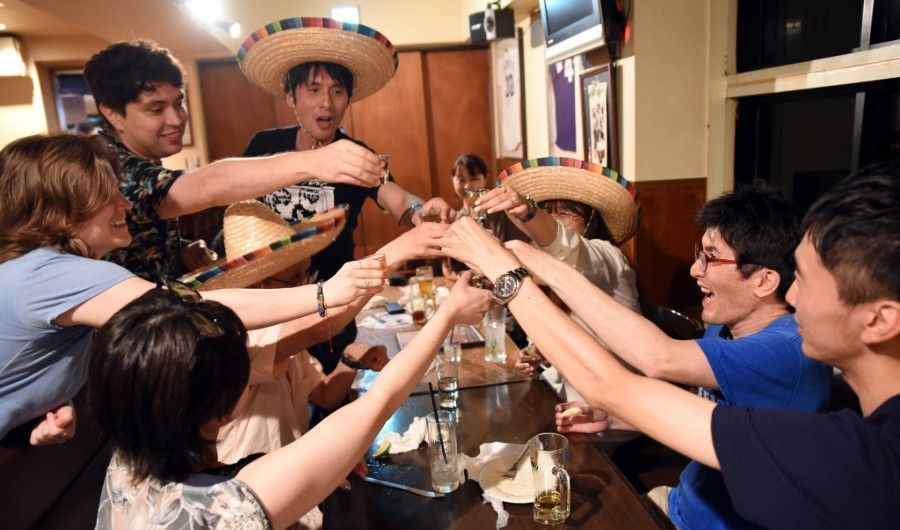 A group of people are sitting around a table with their hands in the air.