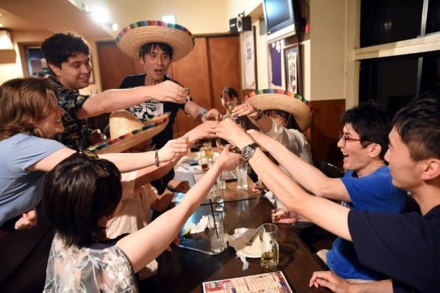 A group of people are sitting around a table with their hands in the air.