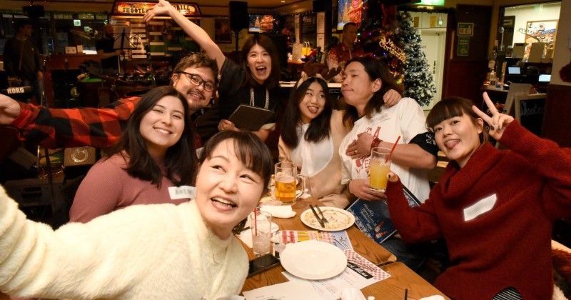 A group of people are sitting around a table taking a selfie.