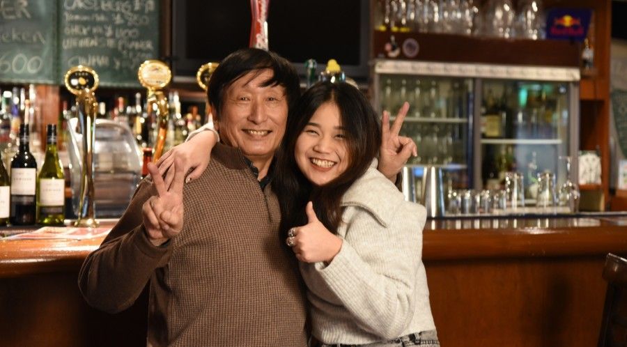 A man and a woman are posing for a picture in a bar.