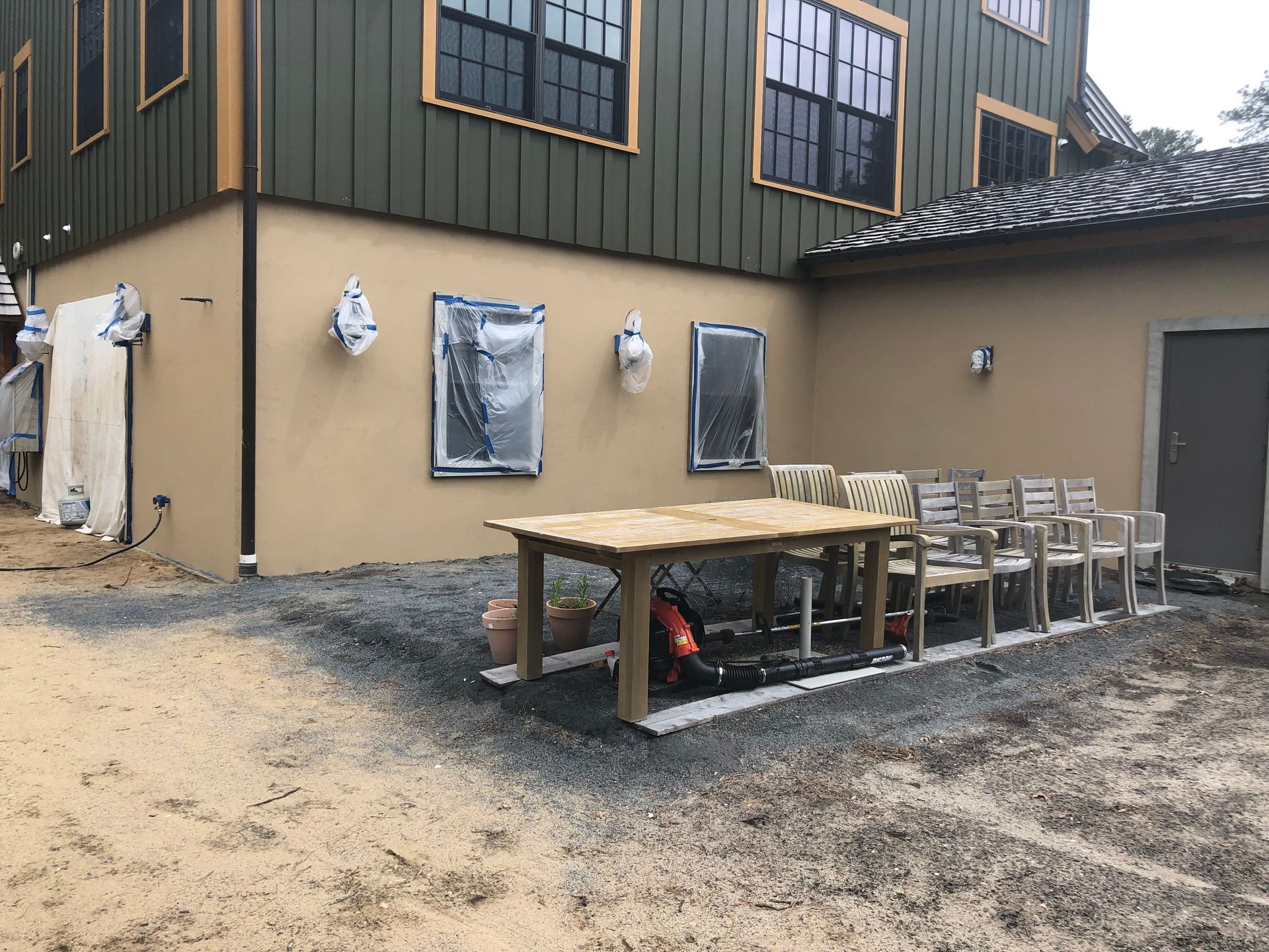 Outdoor seating area next to a building. Table with chairs on gravel, construction in progress.