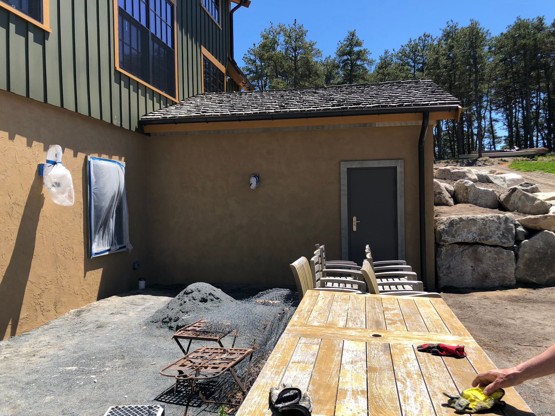 Building exterior with a wooden deck, small stairs, and a dark grey door.